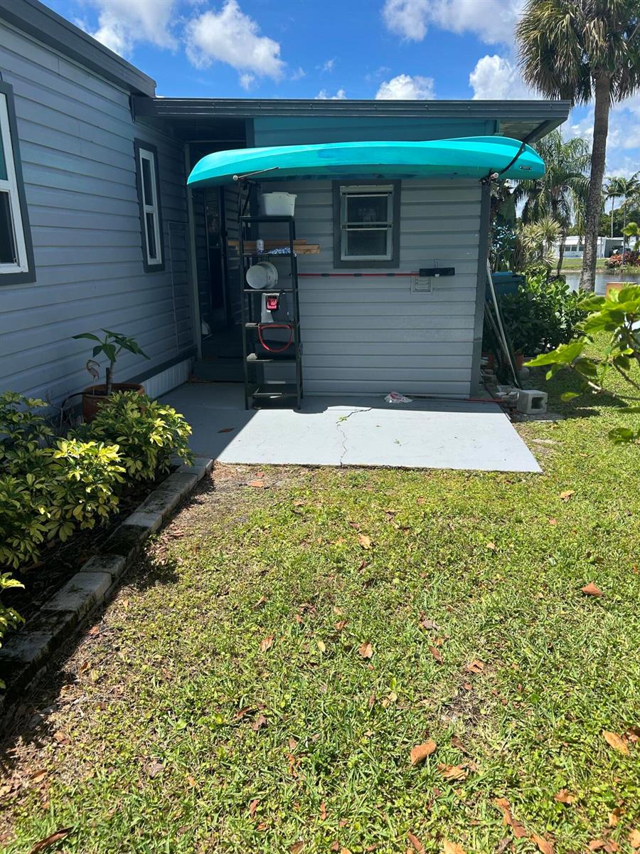 A turquoise kayak is stored on a rack above a concrete patio beside a house — 8628 Duke Court E, Boynton Beach FL 33436, BOYNTON BEACH, FL
