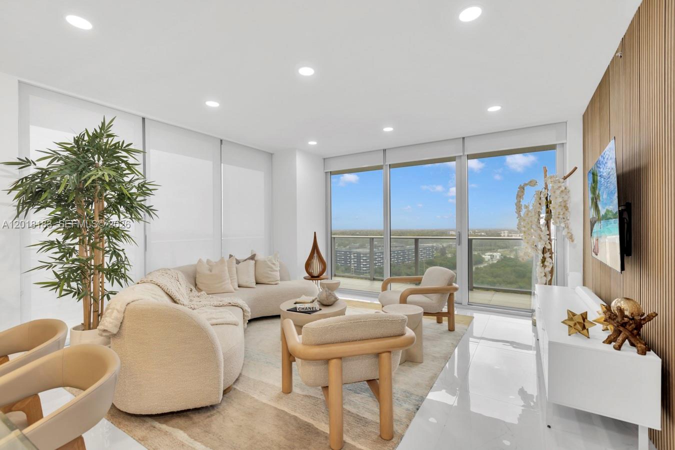 A modern living room features a curved sofa, neutral furniture, and floor-to-ceiling windows with views — 16385 Biscayne Blvd # 2101, North Miami Beach FL 33160, NORTH MIAMI BEACH, FL