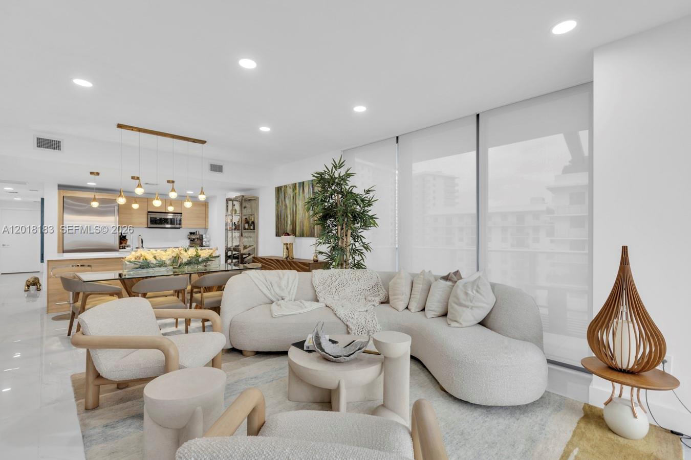 A modern living room features a curved sofa, light-toned furniture, and an open kitchen area — 16385 Biscayne Blvd # 2101, North Miami Beach FL 33160, NORTH MIAMI BEACH, FL