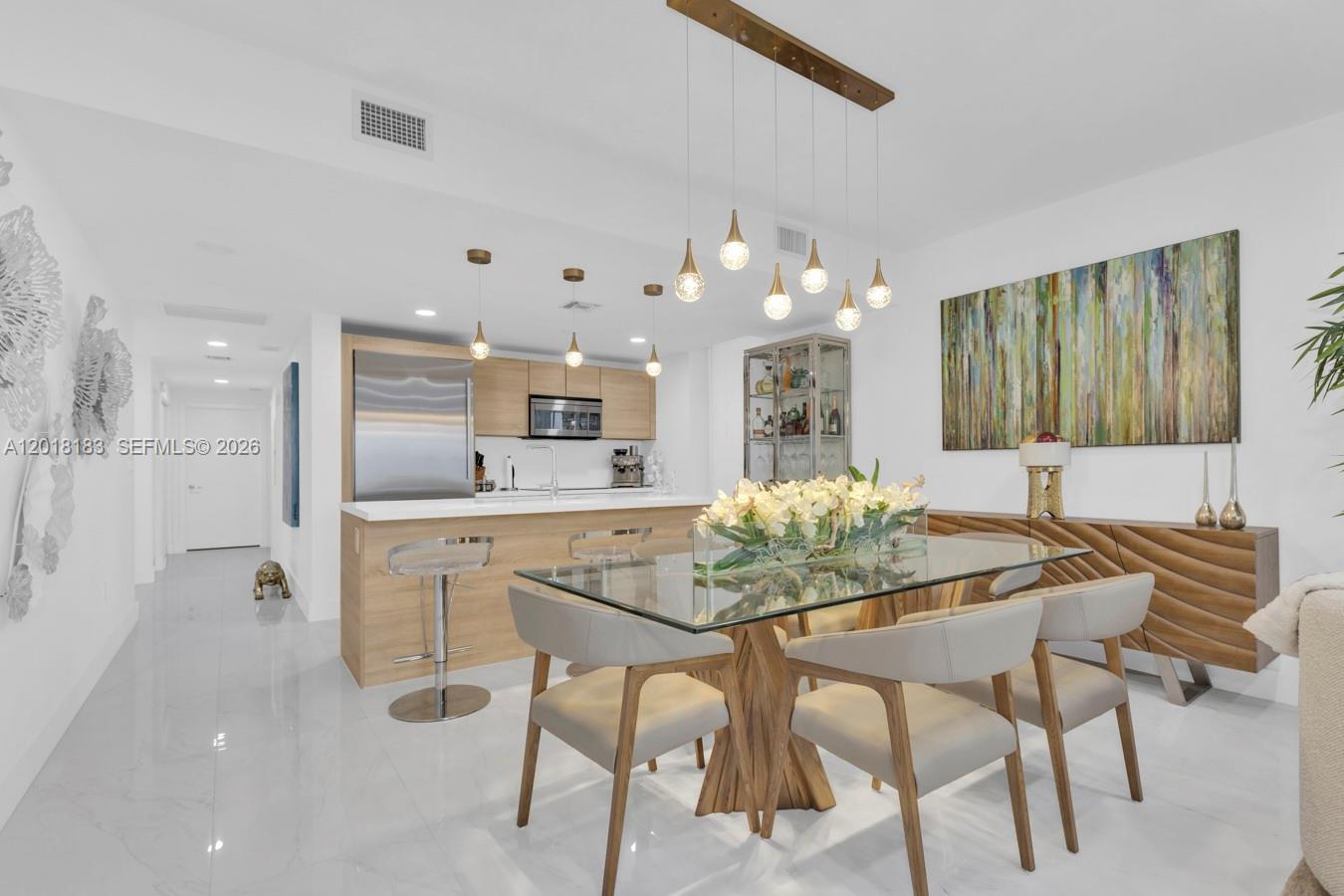 A modern dining area features a glass table, light wood chairs, and an open kitchen — 16385 Biscayne Blvd # 2101, North Miami Beach FL 33160, NORTH MIAMI BEACH, FL