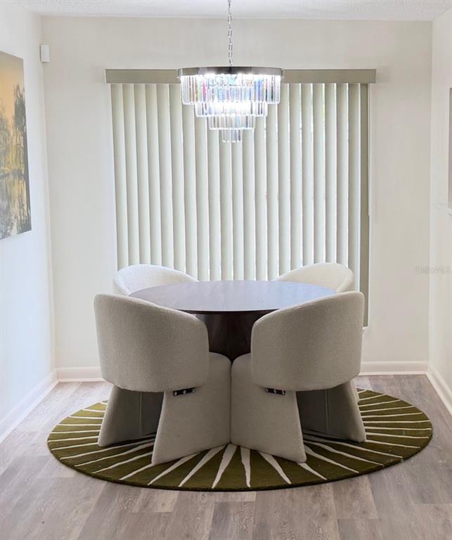 A dining area features a round table, four upholstered chairs, and a tiered crystal chandelier — 10485 CARROLLBROOK CIRCLE UNIT 120, TAMPA, FL