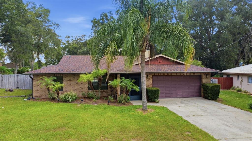 A single-story brick house with a two-car garage, a palm tree, and a grassy lawn — 226 COUNCIL BLUFFS DRIVE, DELTONA, FL