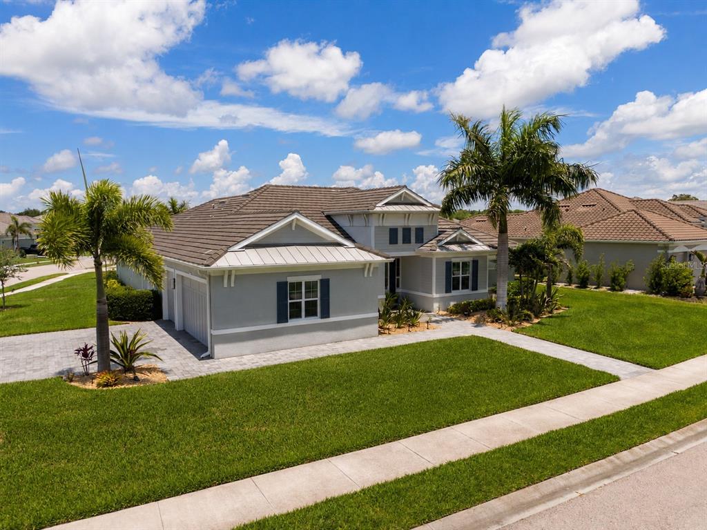 A single-story gray house with a tiled roof, garage, and palm trees on a lawn — 7181 RYEDALE COURT, SARASOTA, FL
