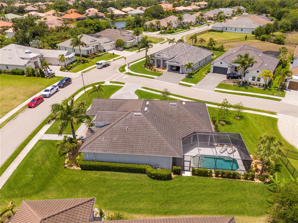 An aerial view shows a suburban house with a dark roof and a screened-in pool — 7181 RYEDALE COURT, SARASOTA, FL