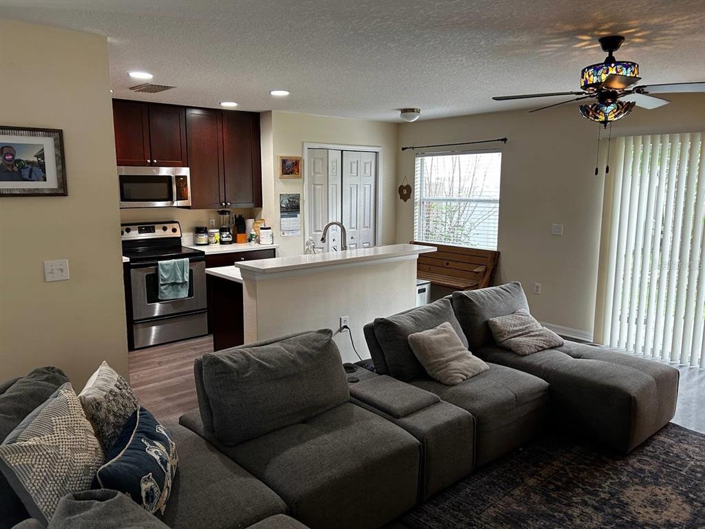 A living room with a gray sectional sofa opens to a kitchen with dark cabinetry — 5085 KINGSCREST LANE, OVIEDO, FL