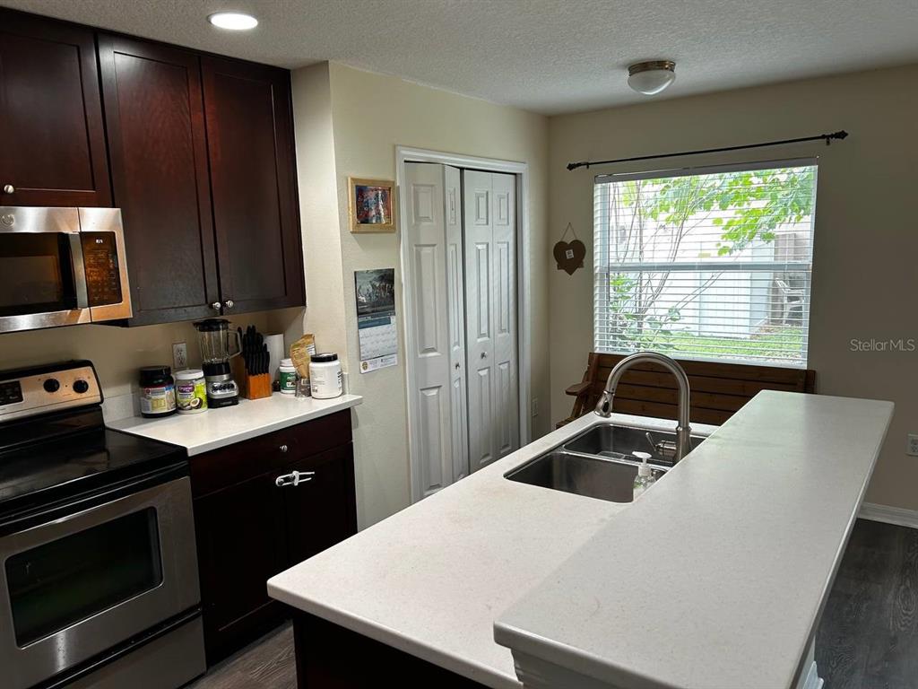 A kitchen features dark wood cabinets, white countertops, stainless steel appliances, and a double sink — 5085 KINGSCREST LANE, OVIEDO, FL