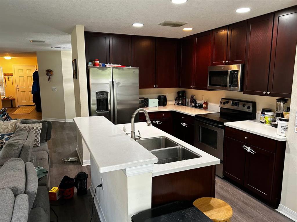 A kitchen features dark wood cabinets, stainless steel appliances, and a white countertop island — 5085 KINGSCREST LANE, OVIEDO, FL