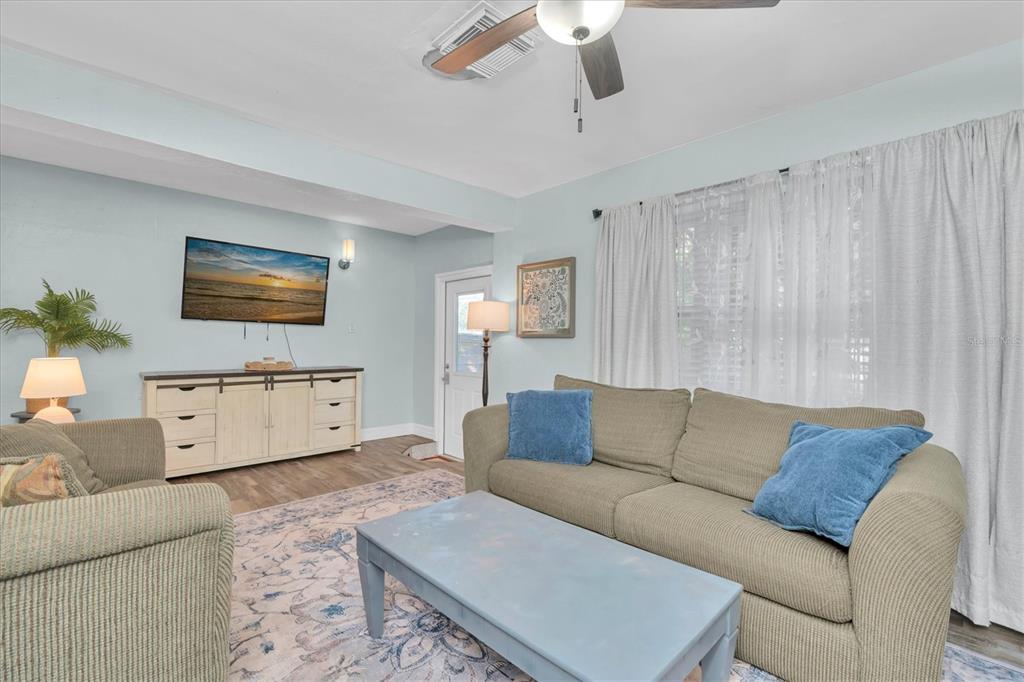 A living room features a beige sofa, a blue coffee table, and a wall-mounted television — 2925 PARK STREET N, ST PETERSBURG, FL