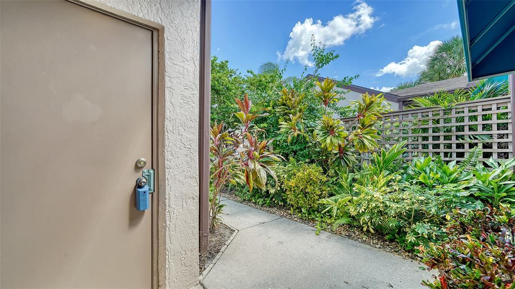 A concrete walkway leads to the garage and entrance of a single-story home — 5956 CLUBSIDE DRIVE UNIT 7651, SARASOTA, FL