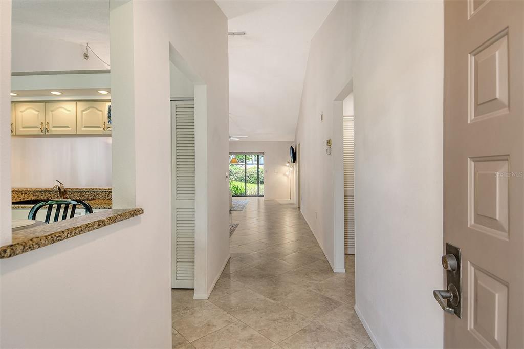 A beige door with a lockbox opens to a paved walkway surrounded by lush tropical plants — 5956 CLUBSIDE DRIVE UNIT 7651, SARASOTA, FL