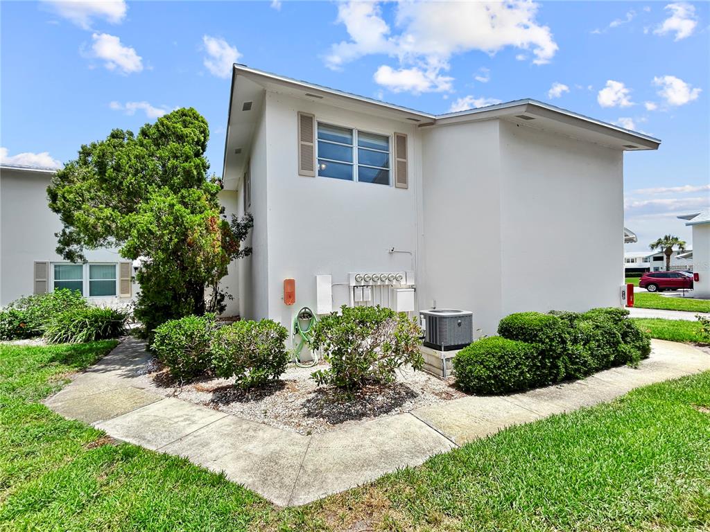 The exterior of a white building features a window, landscaping, and an air conditioning unit — 3265 40TH WAY S UNIT E, ST PETERSBURG, FL