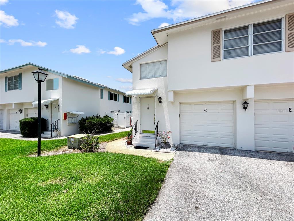 A two-story white townhouse exterior features a gravel driveway, a garage, and a front entrance — 3265 40TH WAY S UNIT E, ST PETERSBURG, FL