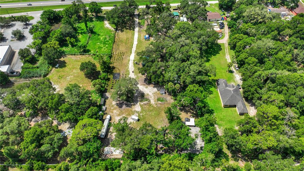 An aerial view shows a large, wooded property with a house, outbuildings, and dirt paths — 9922 ROCKHILL ROAD, THONOTOSASSA, FL
