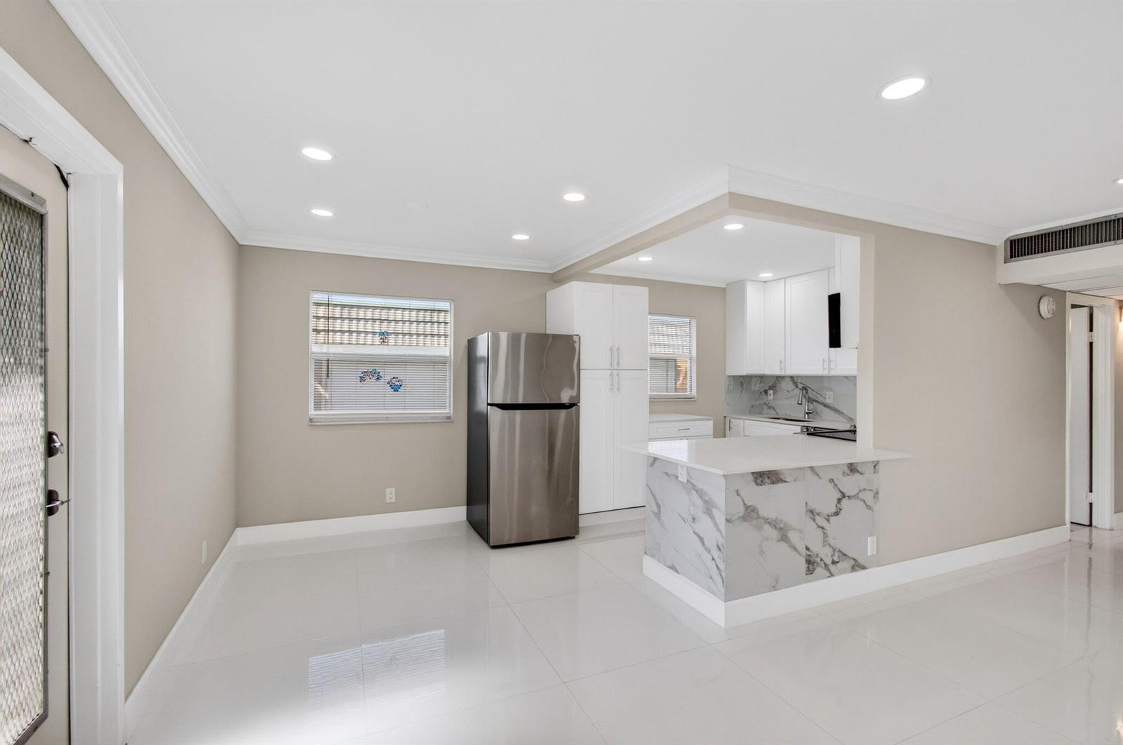 A kitchen features white cabinets, stainless steel appliances, and a marble-patterned island countertop — 429 Flanders I, Delray Beach FL 33484, DELRAY BEACH, FL