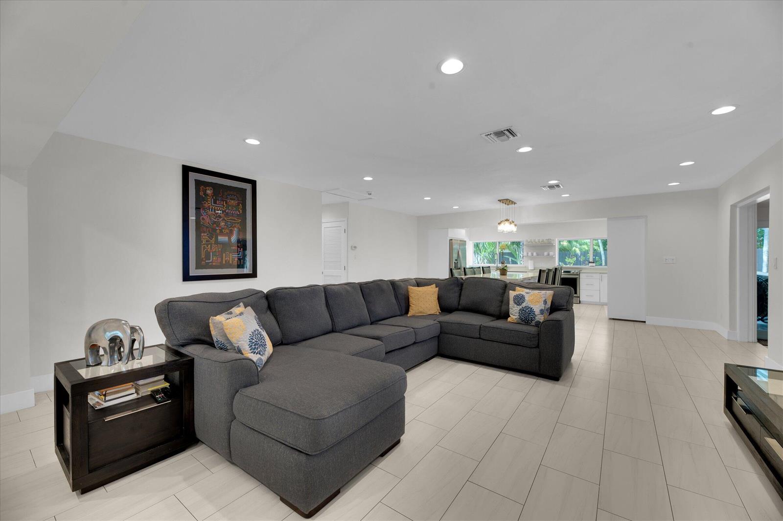 A spacious living room features a large gray sectional sofa and light tile flooring — 2633 NE 3rd Avenue, Wilton Manors FL 33334, WILTON MANORS, FL