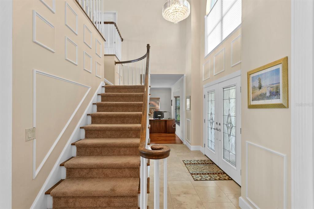 A foyer features a carpeted staircase, tile flooring, a crystal chandelier, and a front door — 13548 LAKE MAGDALENE DRIVE, TAMPA, FL