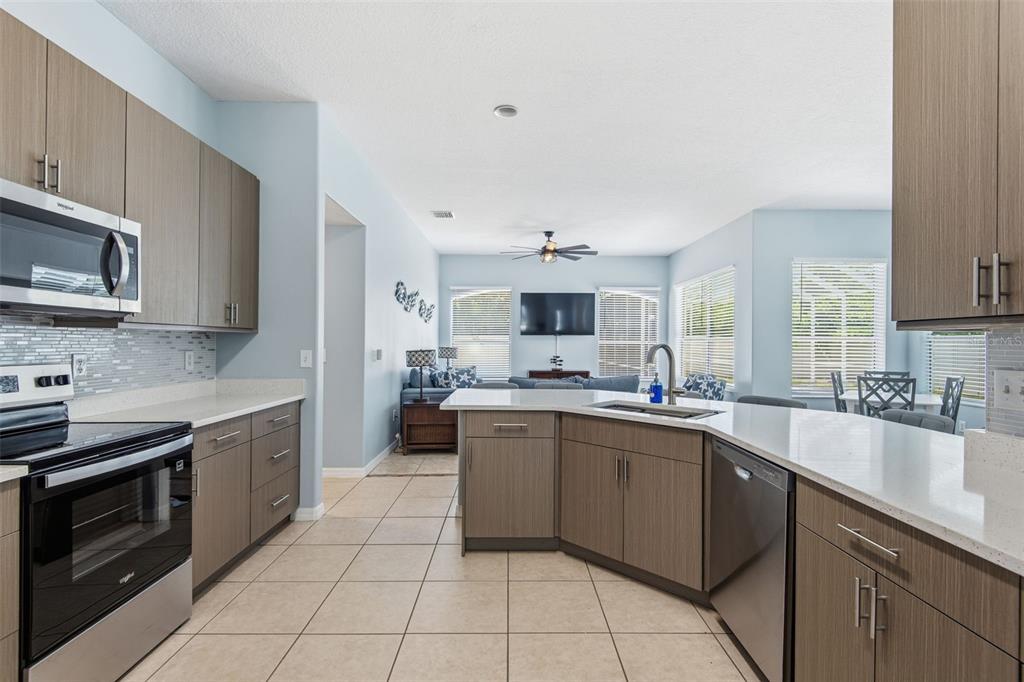 A kitchen with wood-tone cabinets, stainless steel appliances, and a peninsula overlooking a living area — 6 BURRELL PLACE, PALM COAST, FL