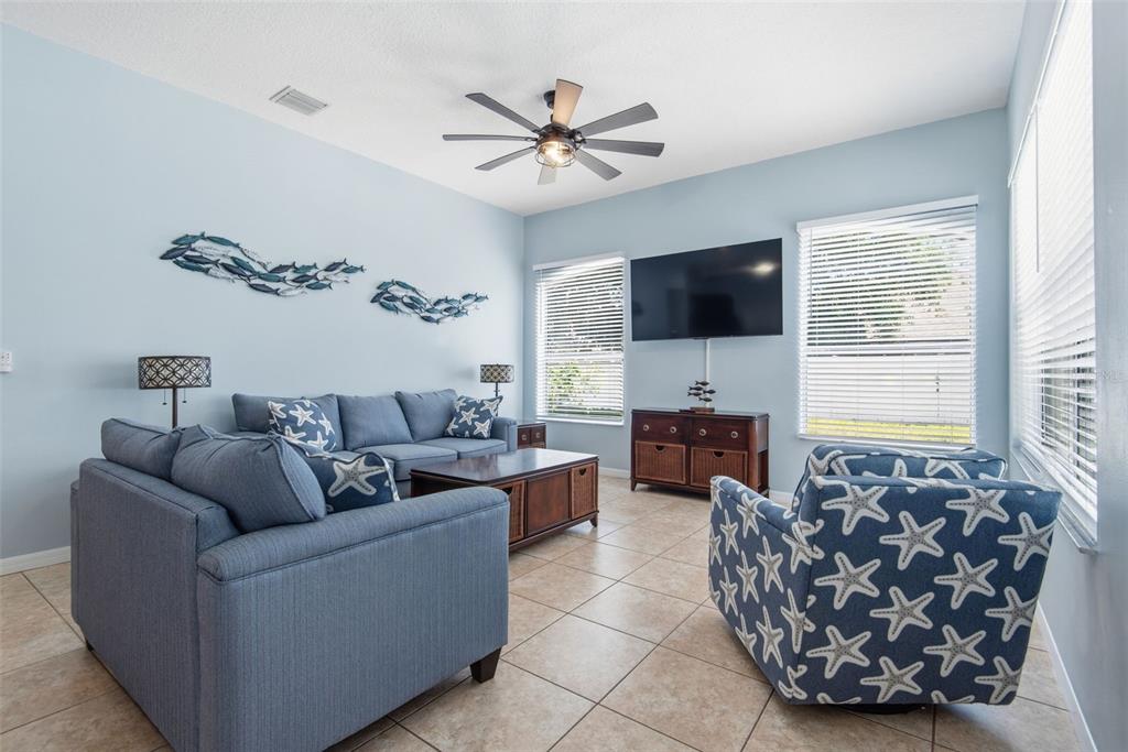A living room features light blue walls, a blue sofa, a starfish-patterned chair, and tile flooring — 6 BURRELL PLACE, PALM COAST, FL