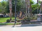 A metal gate stands before a landscaped entrance with palm trees and a circular sign — 36 OLD OAK DRIVE S, PALM COAST, FL