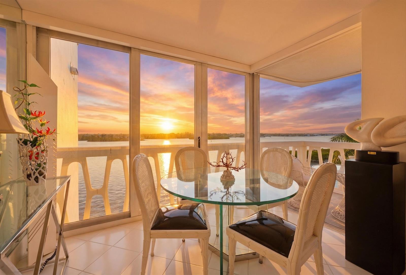 A dining area with a glass table and chairs overlooks a sunset over the water — 2505 S Ocean Boulevard, Palm Beach FL 33480, PALM BEACH, FL