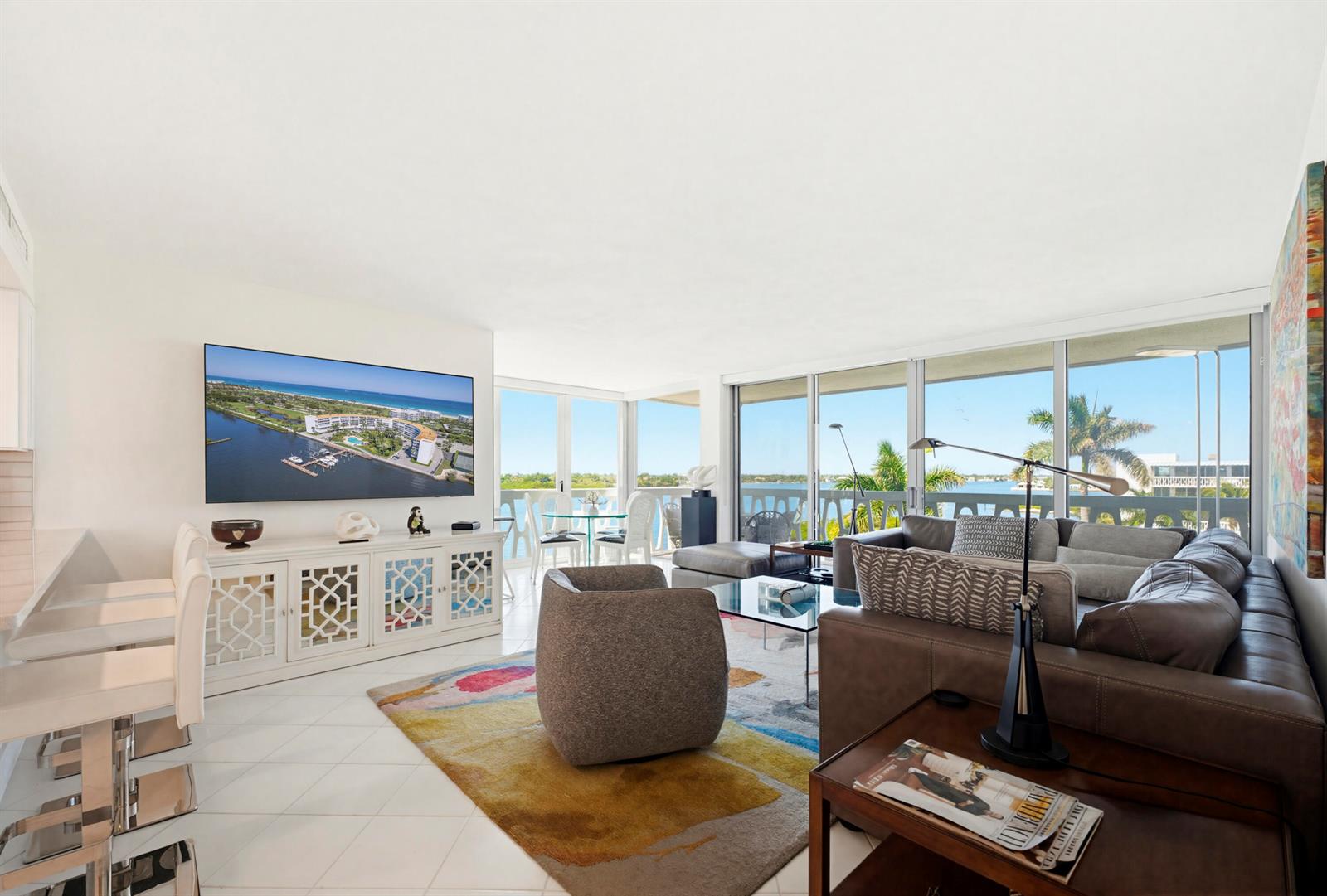 A bright living room features a large television, leather sofa, patterned rug, and floor-to-ceiling windows — 2505 S Ocean Boulevard, Palm Beach FL 33480, PALM BEACH, FL