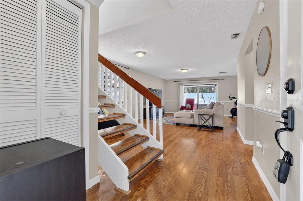 An entryway leads to a living room with wood flooring and a staircase with wooden treads — 5215 CORVETTE DRIVE, TAMPA, FL