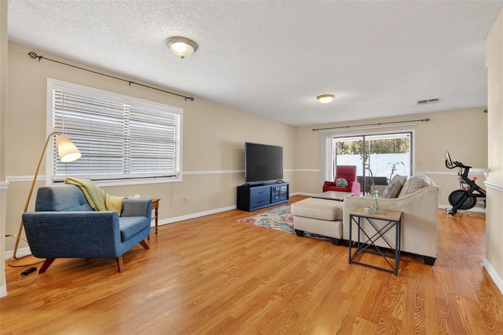 A living room features hardwood floors, a blue armchair, a sectional sofa, and a television — 5215 CORVETTE DRIVE, TAMPA, FL