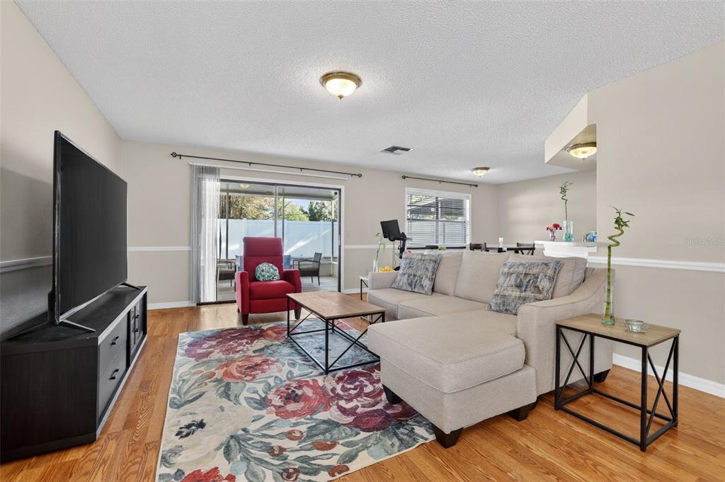 A living room features a sectional sofa, floral area rug, television, and sliding glass doors — 5215 CORVETTE DRIVE, TAMPA, FL