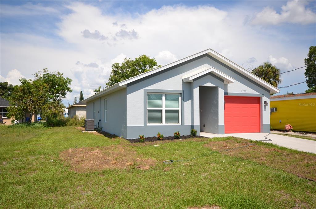 A single-story house with gray stucco walls, a bright red garage door, and a lawn — 2225 CARVER AVENUE, FORT MYERS, FL