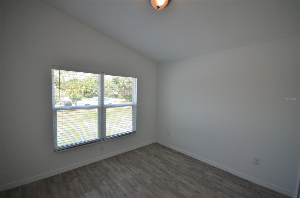 An empty room features white walls, wood-look flooring, and a window with white blinds — 2225 CARVER AVENUE, FORT MYERS, FL