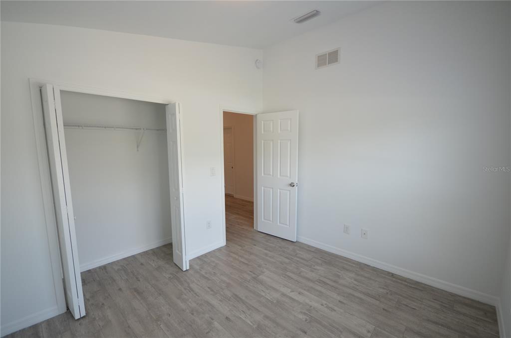 An empty bedroom features light wood-look flooring, white walls, a closet, and an open doorway — 2225 CARVER AVENUE, FORT MYERS, FL