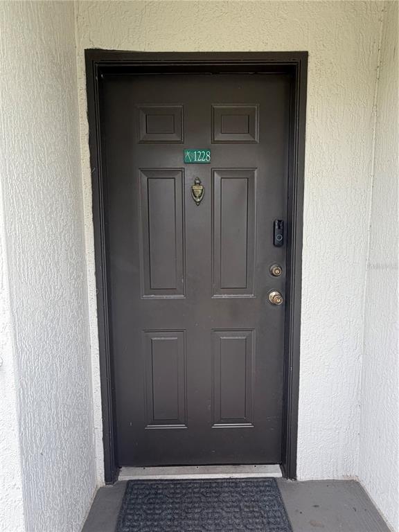 A dark brown, six-panel front door with a door knocker and smart doorbell — 13827 FAIRWAY ISLAND DRIVE UNIT 1228, ORLANDO, FL