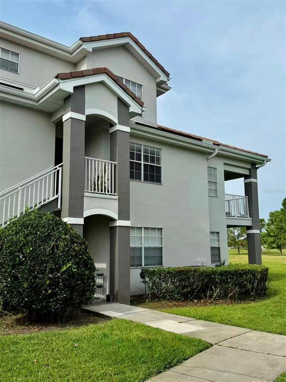 A multi-story apartment building features light gray stucco walls, dark gray accents, and exterior staircases — 13827 FAIRWAY ISLAND DRIVE UNIT 1228, ORLANDO, FL