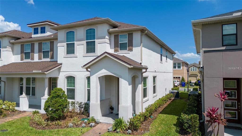 A two-story stucco townhouse with a covered entryway and a small front yard — 2449 VARENNA LOOP, KISSIMMEE, FL