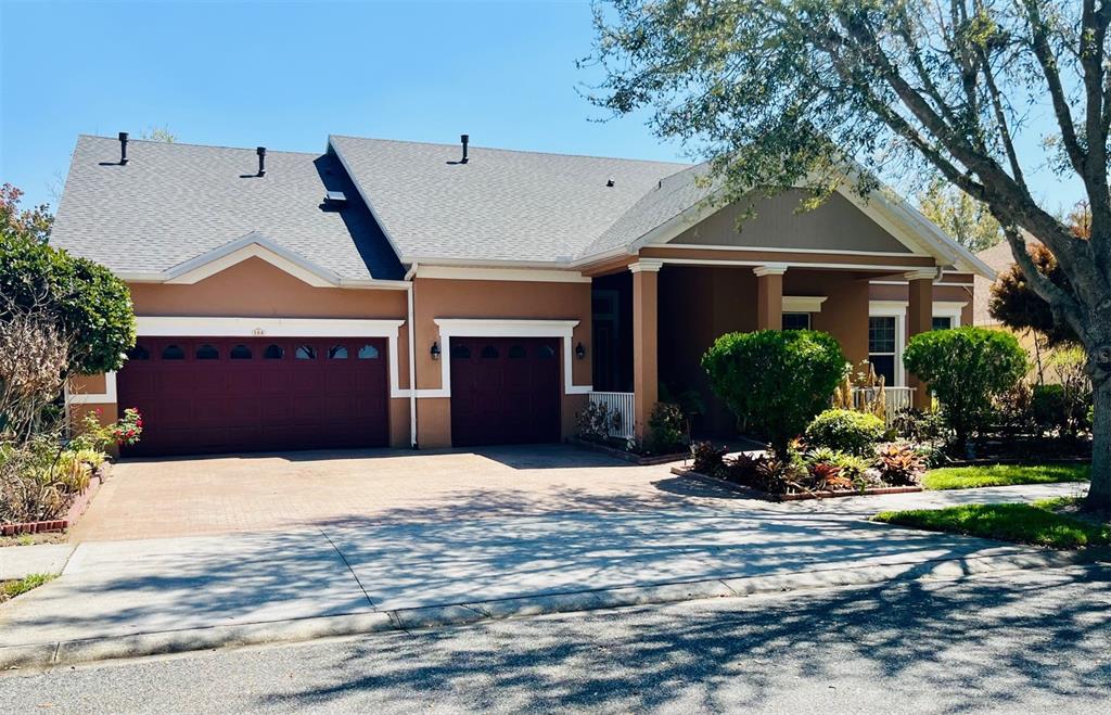 A single-story house with a two-car garage, tan stucco exterior, and a covered front porch — 184 CREPE MYRTLE DRIVE, GROVELAND, FL