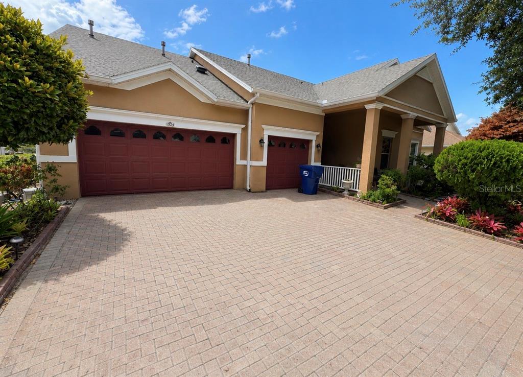 A tan house with a red garage and a paved driveway under a blue sky — 184 CREPE MYRTLE DRIVE, GROVELAND, FL