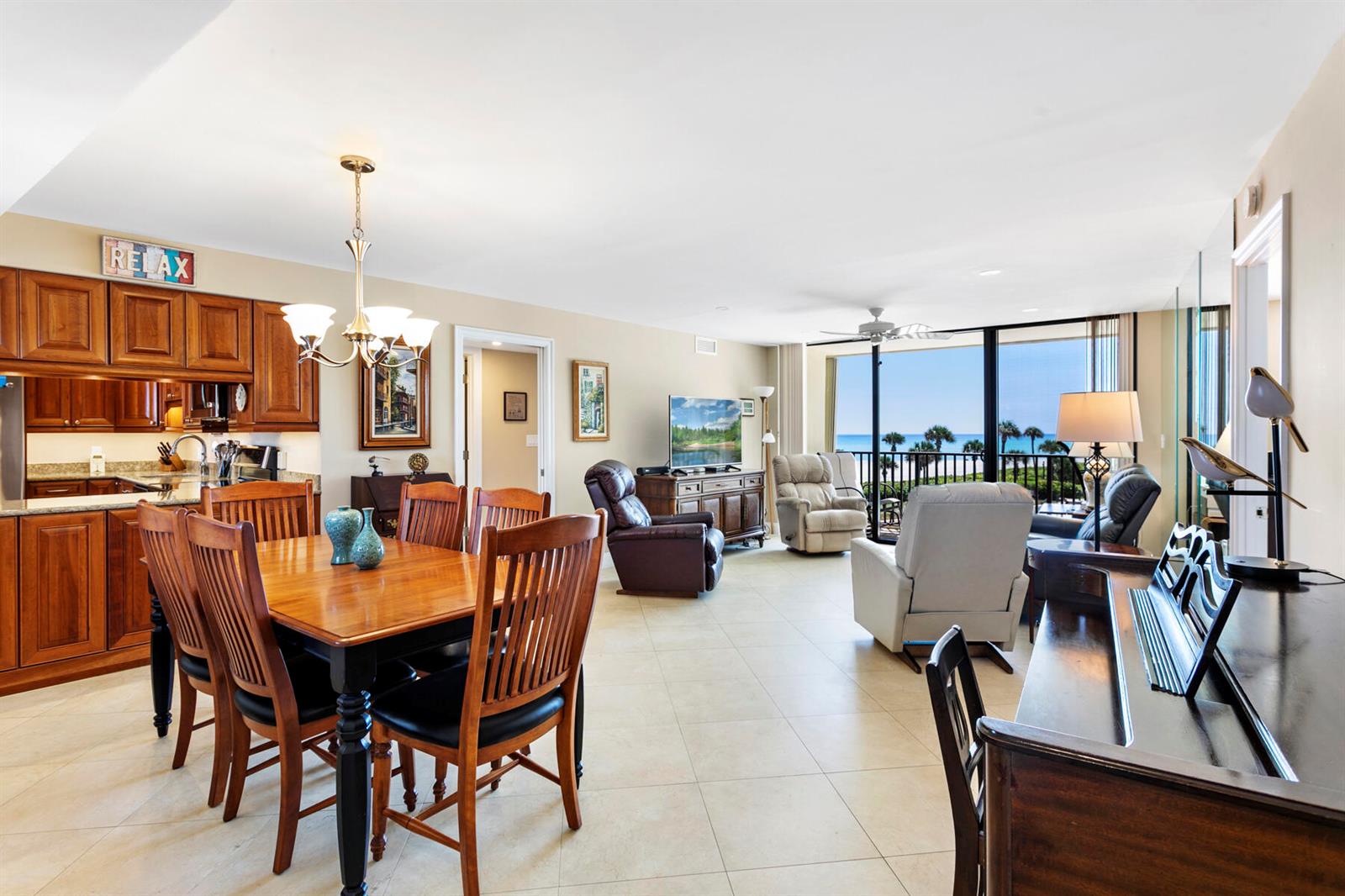 An open-concept living and dining area features wood cabinetry, tile floors, and a balcony view — 400 Ocean Trail Way # 303, Jupiter FL 33477, JUPITER, FL