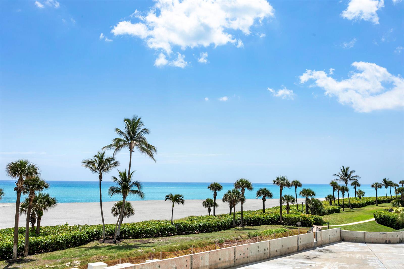 A view of a sandy beach and ocean from a balcony with palm trees — 400 Ocean Trail Way # 303, Jupiter FL 33477, JUPITER, FL