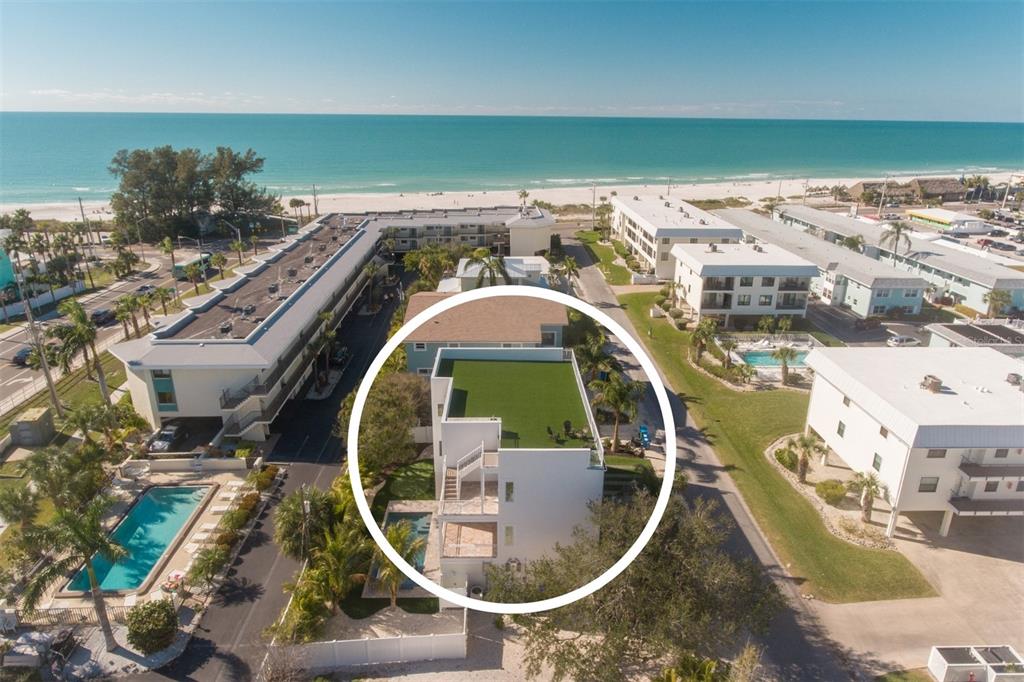 An aerial view shows a white multi-story house with a rooftop terrace and private pool — 111 6TH STREET N, BRADENTON BEACH, FL