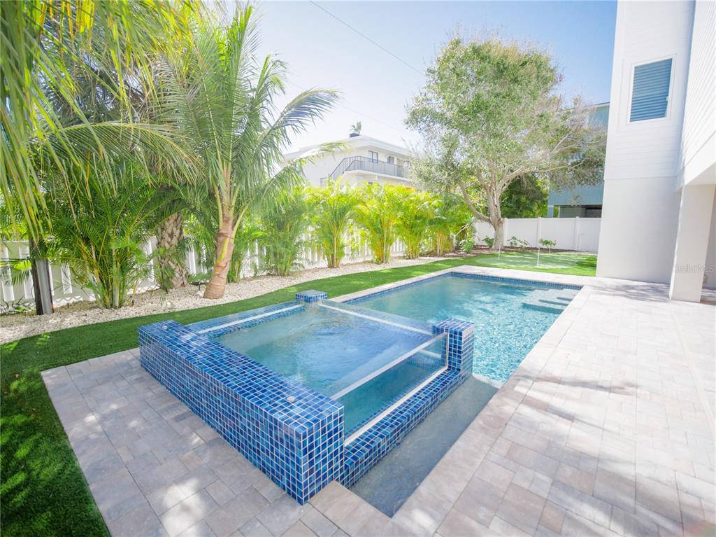 A backyard features a swimming pool with an attached raised spa and blue tile accents — 111 6TH STREET N, BRADENTON BEACH, FL