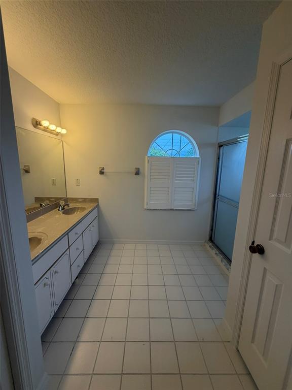 A bathroom features white cabinets, a tiled floor, a vanity mirror, and an arched window — 2 LAMAR LANE, PALM COAST, FL