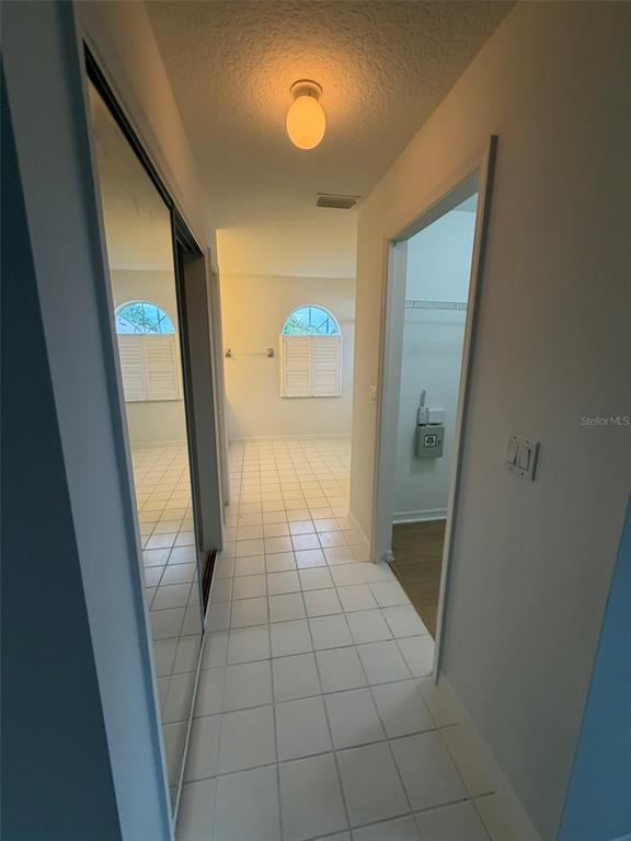 A hallway with white tile flooring leads to a room featuring two arched windows — 2 LAMAR LANE, PALM COAST, FL
