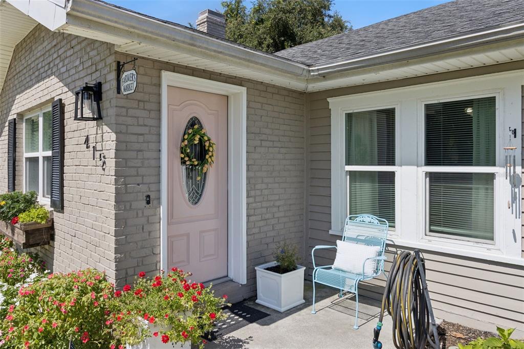 A light pink front door is set into a grey brick and siding house exterior — 415 8TH STREET NE, WINTER HAVEN, FL