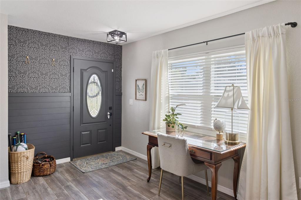 A home entryway features a dark accent wall with wallpaper, a desk, and a front door — 415 8TH STREET NE, WINTER HAVEN, FL