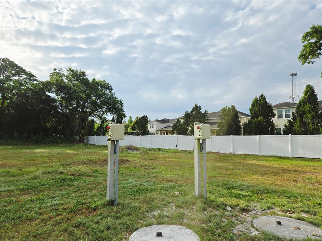 An open grassy lot features two utility pedestals and concrete covers in the foreground — 14701 DEL VALLE ROAD, TAMPA, FL