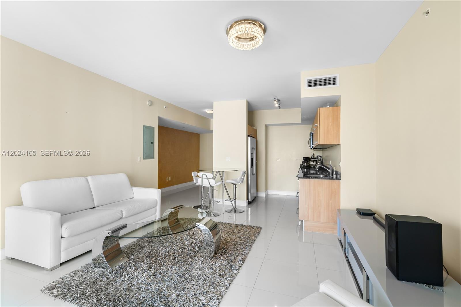 A living room with a white sofa, glass coffee table, and an adjacent kitchenette — 350 S Miami Ave # 2515, Miami FL 33130, MIAMI, FL