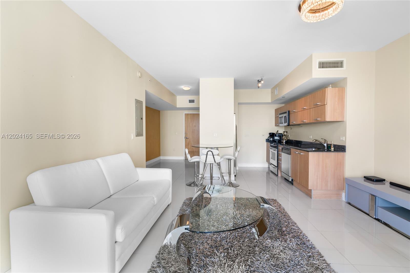 A living room features a white sofa, glass coffee table, and an adjacent kitchen area — 350 S Miami Ave # 2515, Miami FL 33130, MIAMI, FL
