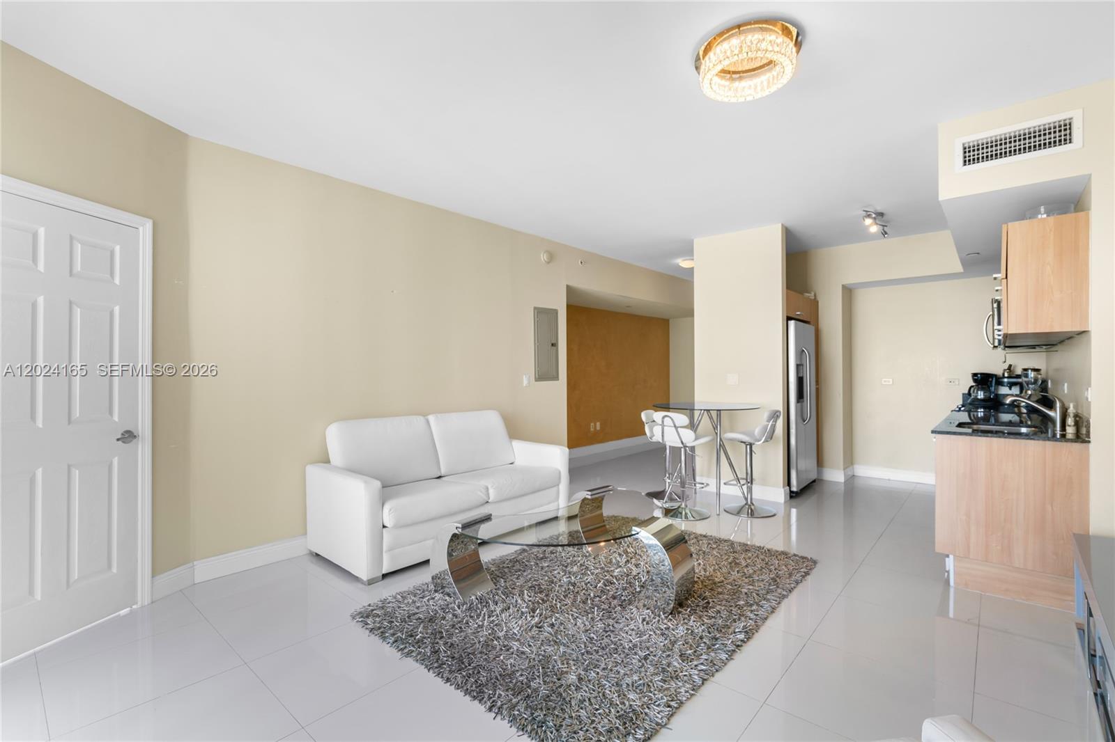 A living room features a white sofa, glass coffee table, and a small dining area — 350 S Miami Ave # 2515, Miami FL 33130, MIAMI, FL
