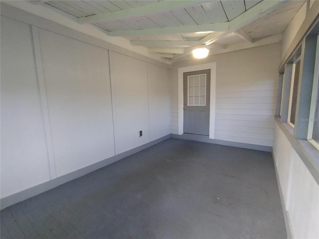 A covered porch features gray painted walls, a concrete floor, and a single entry door — 100 S STONE STREET UNIT A, BUNNELL, FL