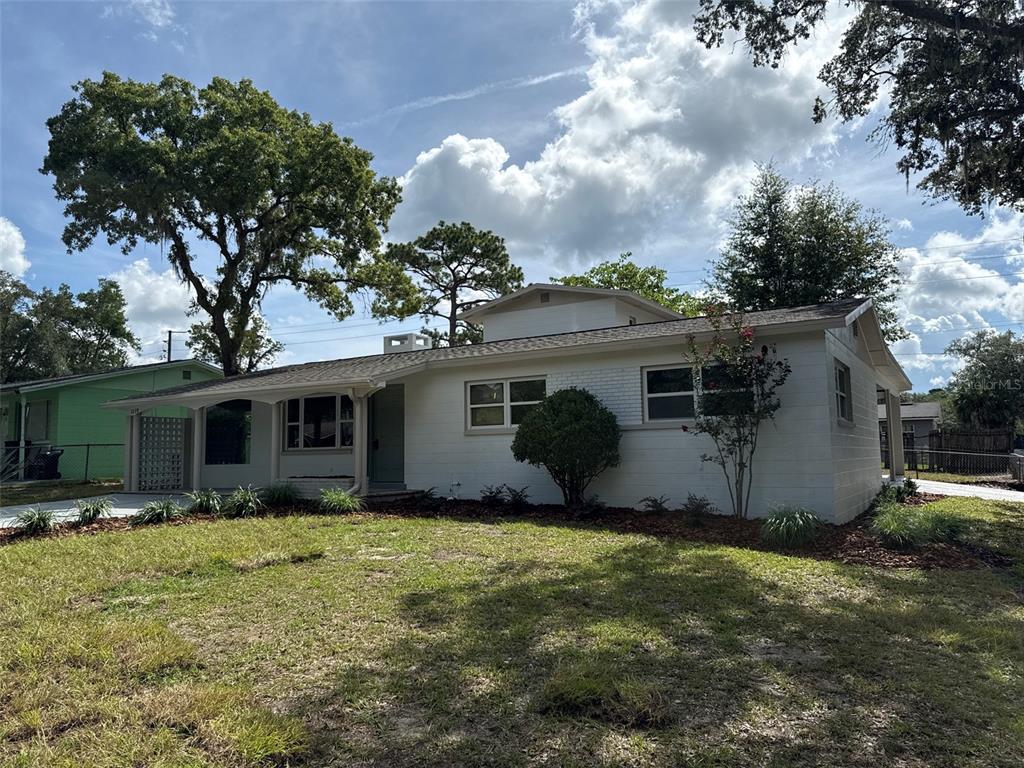 A white, single-story house with a brick exterior, a covered porch, and a large tree — 1239 SE 18TH TERRACE, GAINESVILLE, FL